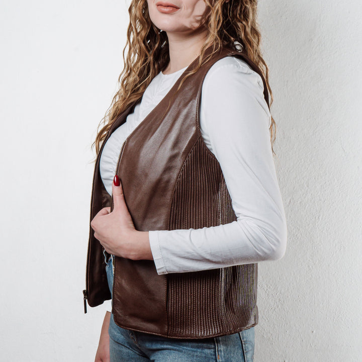 Mujer usando chaleco de piel de borrego cafe 'Silueta' de Gerhel con ajuste lateral.