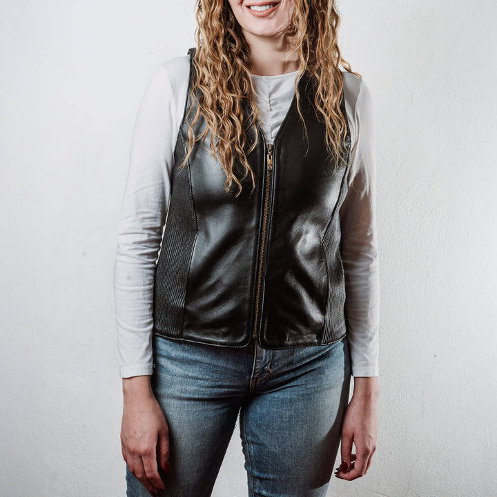 Mujer usando chaleco de piel de borrego negro 'Silueta' de Gerhel con ajuste lateral.