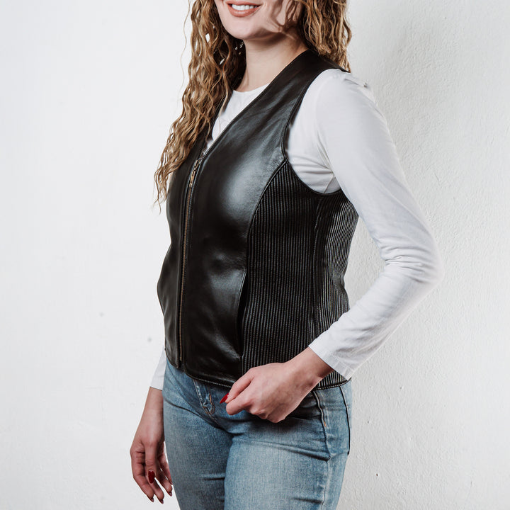 Mujer usando chaleco de piel de borrego negro 'Silueta' de Gerhel con ajuste lateral.