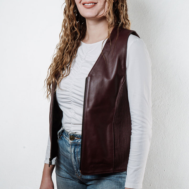 Mujer usando chaleco de piel de borrego vino 'Silueta' de Gerhel con ajuste lateral.