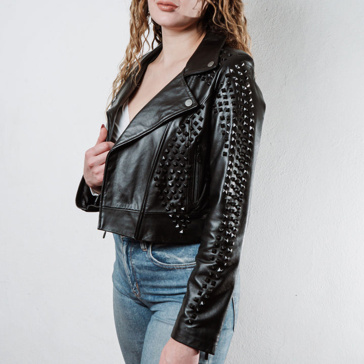Mujer usando chamarra biker de piel negra con estoperoles negros modelo 'Rockstar Oscura' de Gerhel.