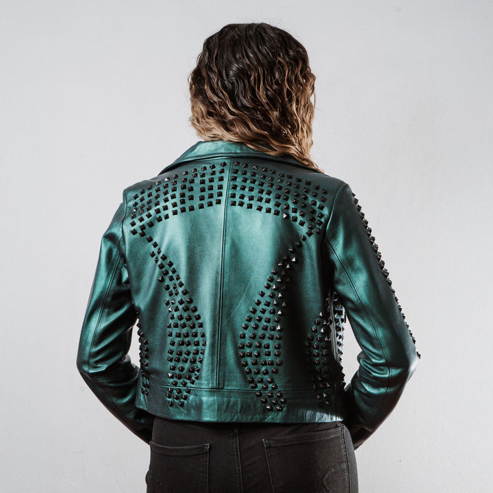 Mujer usando chamarra biker de piel verde metálico con estoperoles negros modelo 'Rockstar' de Gerhel. Vista trasera.